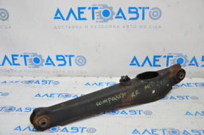 The lower rear right control arm of a Jeep Compass 11-16 is rusty.