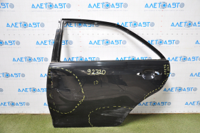The bare rear left door of a Toyota Camry v40 is black and dented.