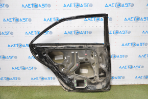 The bare rear left door of a Toyota Camry v40 is black and dented.