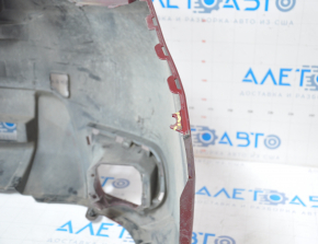 The front bumper of a Subaru Forester 14-16 SJ pre-rest red is dented, has tears, broken fasteners, and scratches.