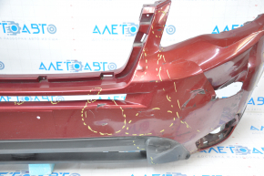 The front bumper of a Subaru Forester 14-16 SJ pre-rest red is dented, has tears, broken fasteners, and scratches.