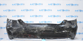 The rear bumper of a Toyota Camry V55 15-17 USA is black and dented, torn, and has broken fasteners.