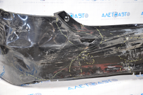 The rear bumper of a Toyota Camry V55 15-17 USA is black and dented, torn, and has broken fasteners.