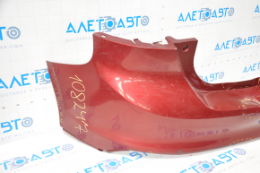 The rear bumper of a Ford Focus mk3 11-14 pre-restoration 5d red is dented, has tears, and has broken fasteners.