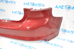 The rear bumper of a Ford Focus mk3 11-14 pre-restoration 5d red is dented, has tears, and has broken fasteners.