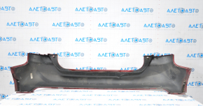 The rear bumper of a Ford Focus mk3 11-14 pre-restoration 5d red is dented, has tears, and has broken fasteners.