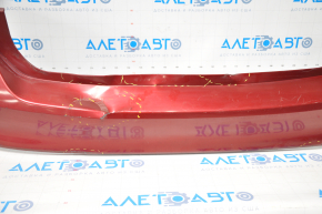 The rear bumper of a Ford Focus mk3 11-14 pre-restoration 5d red is dented, has tears, and has broken fasteners.