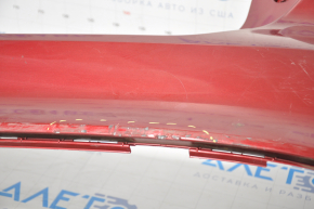 The rear bumper of a Ford Focus mk3 11-14 pre-restoration 5d red is dented, has tears, and has broken fasteners.