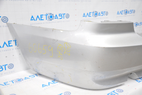 The rear bumper of a BMW 335i e92 07-10 silver is dented, sawed, and has broken fasteners.