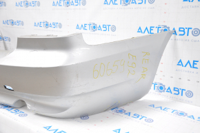 The rear bumper of a BMW 335i e92 07-10 silver is dented, sawed, and has broken fasteners.
