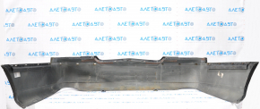 The rear bumper of a 98-11 Lincoln Town Car is bare and black, dented, with torn fasteners and missing right molding.