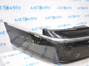 The rear bumper of a 98-11 Lincoln Town Car is bare and black, dented, with torn fasteners and missing right molding.