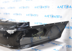 The rear bumper of a 98-11 Lincoln Town Car is bare and black, dented, with torn fasteners and missing right molding.