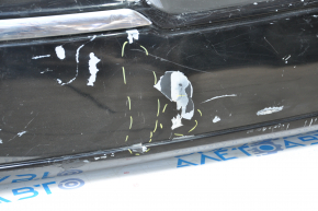 The rear bumper of a 98-11 Lincoln Town Car is bare and black, dented, with torn fasteners and missing right molding.