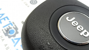 The driver's side airbag in the Jeep Grand Cherokee WK2 14-18 steering wheel is black, scratched, and has a rusty squib.