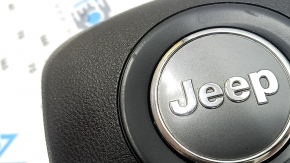 The driver's side airbag in the Jeep Grand Cherokee WK2 14-18 steering wheel is black, scratched, and has a rusty squib.