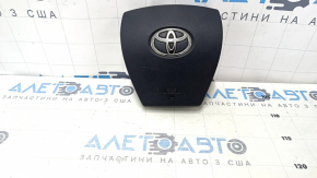 The driver's side airbag in the steering wheel of a Toyota Prius V 12-17 is black and scratched.