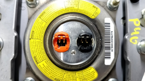 The driver's side airbag in the steering wheel of a Toyota Prius V 12-17 is black and scratched.