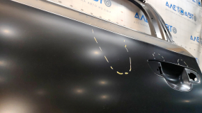 The front left door of a VW Passat b7 12-15 USA is bare and dented.