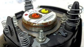 The driver's side steering wheel airbag for a Nissan Rogue 17-20 is black, has scratches, and is rusty.
