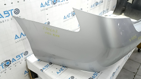 The rear bumper of a Toyota Camry V40 hybrid is bare, silver, pressed, and has cracks.