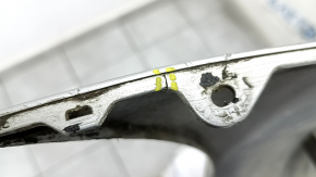 The rear bumper of a Toyota Camry V40 hybrid is bare, silver, pressed, and has cracks.