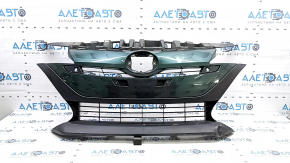 The radiator grill of a Toyota Prius 50 Prime 17-19 under parking sensors is cracked and dented.