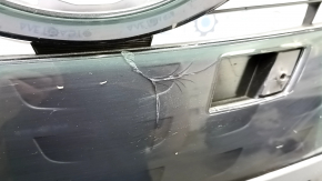 The radiator grill of a Toyota Prius 50 Prime 17-19 under parking sensors is cracked and dented.