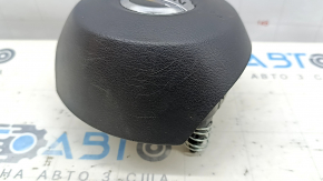 The driver's side airbag in the steering wheel of a Nissan Rogue 17-20 is black and scratched.