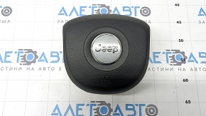 The Jeep Cherokee KL 19-23 driver's steering wheel airbag is black and has a rusty squib.