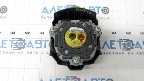 The driver's side airbag in the steering wheel of a 1995 Subaru Outback is black and has a rusty squib.