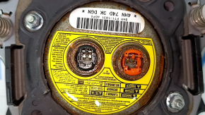 The driver's side airbag in the steering wheel of a 1995 Subaru Outback is black and has a rusty squib.