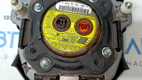 The driver's side airbag in the steering wheel of a 1995 Subaru Outback is black and has a rusty squib.