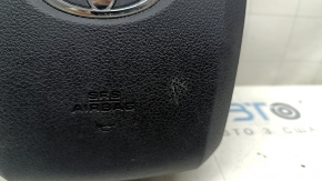 The airbag in the driver's steering wheel of a Toyota Prius 50 16-22 is black and scratched.
