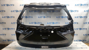 The trunk door of a Ford Edge 19-24 is bare and dented.