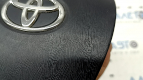 The driver's side airbag in the Toyota Prius V 12-17 is black, scratched, and has a rusty squib.
