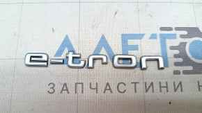 The E-TRON emblem on the Audi E-Tron 19-23 trunk door is chrome.
