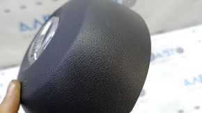 The driver's side airbag in the steering wheel of a Nissan Rogue Sport 20-22 is black and scratched.