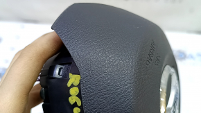 The driver's side airbag in the steering wheel of a Nissan Rogue Sport 20-22 is black and scratched.