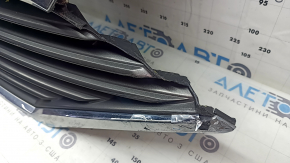 The grille assembly with the Nissan Quest 12-14 badge, camera, and molding is broken, worn, missing a fragment, broken fasteners, and peeling chrome.