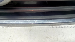 The grille assembly with the Nissan Quest 12-14 badge, camera, and molding is broken, worn, missing a fragment, broken fasteners, and peeling chrome.