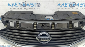 The grille assembly with the Nissan Quest 12-14 badge, camera, and molding is broken, worn, missing a fragment, broken fasteners, and peeling chrome.
