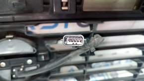 The grille assembly with the Nissan Quest 12-14 badge, camera, and molding is broken, worn, missing a fragment, broken fasteners, and peeling chrome.