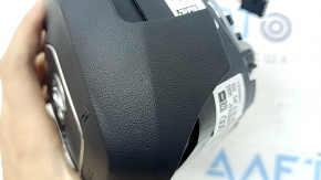 The Audi Q8 19-25 driver's steering wheel airbag is black and scratched.