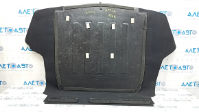 The trunk floor of a 2016-2017 Kia Optima is black, worn, has dents, and needs cleaning.