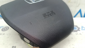 The steering wheel airbag for the driver's side of a 1993 Honda Accord is black and scratched.