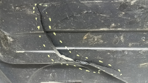 The rear left underbody protection of a BMW X5 G05 19-24 is dented and cracked.