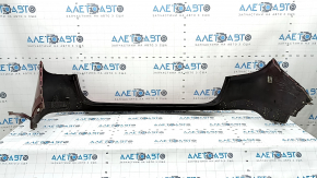 The bare rear bumper of a Buick Encore 17-22 without BSM, without reflector brackets, is dented, torn, has broken fasteners and scratches.