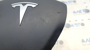 The Tesla Model Y 20-25 driver's steering wheel airbag is black and scratched.
