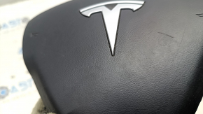 The Tesla Model Y 20-25 driver's steering wheel airbag is black and scratched.